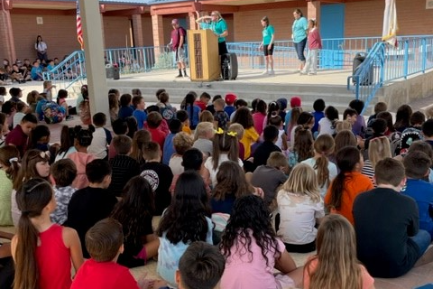 students seated watching a student on stage speak