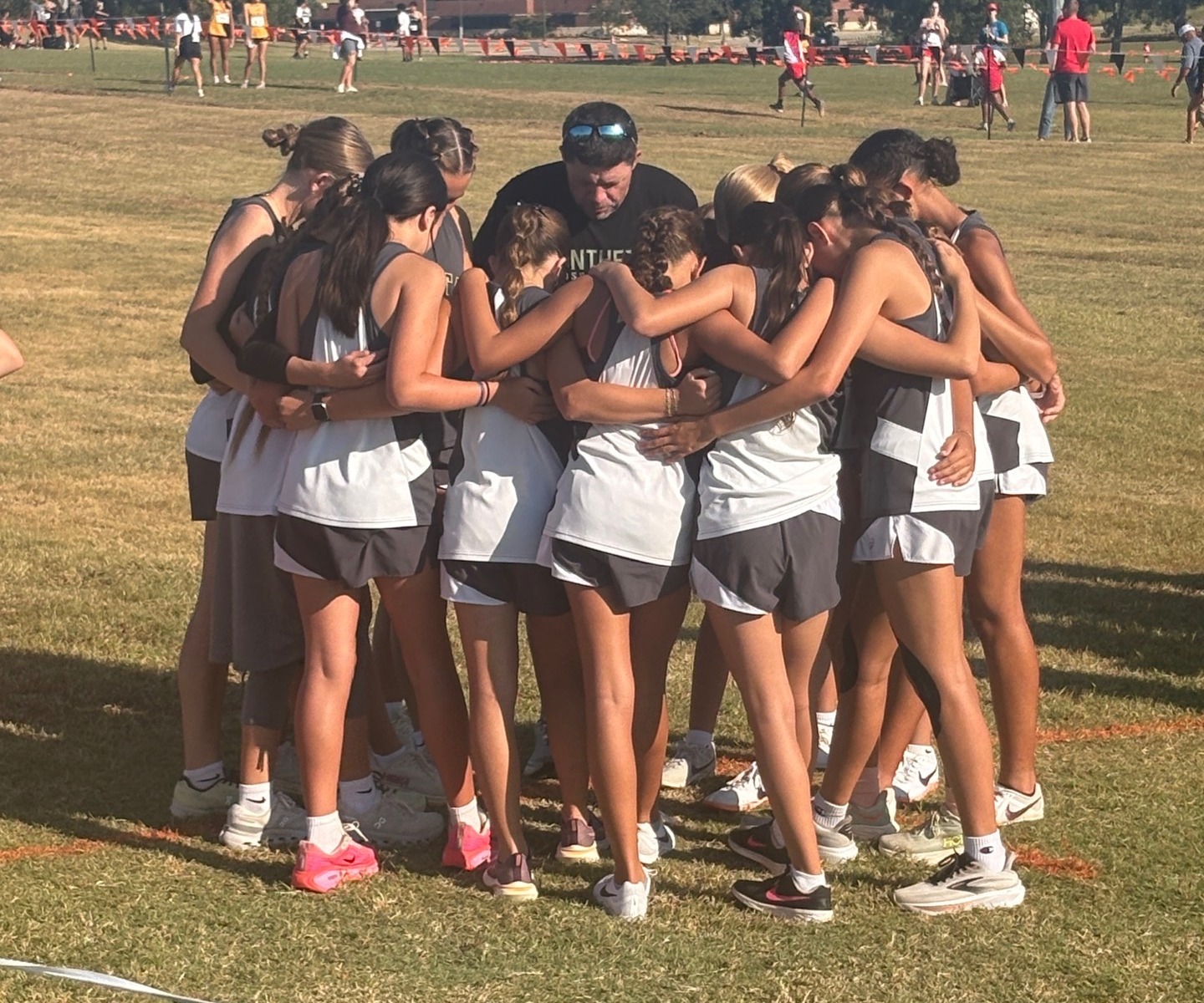 Coach Sullivan praying with the girls cross country team