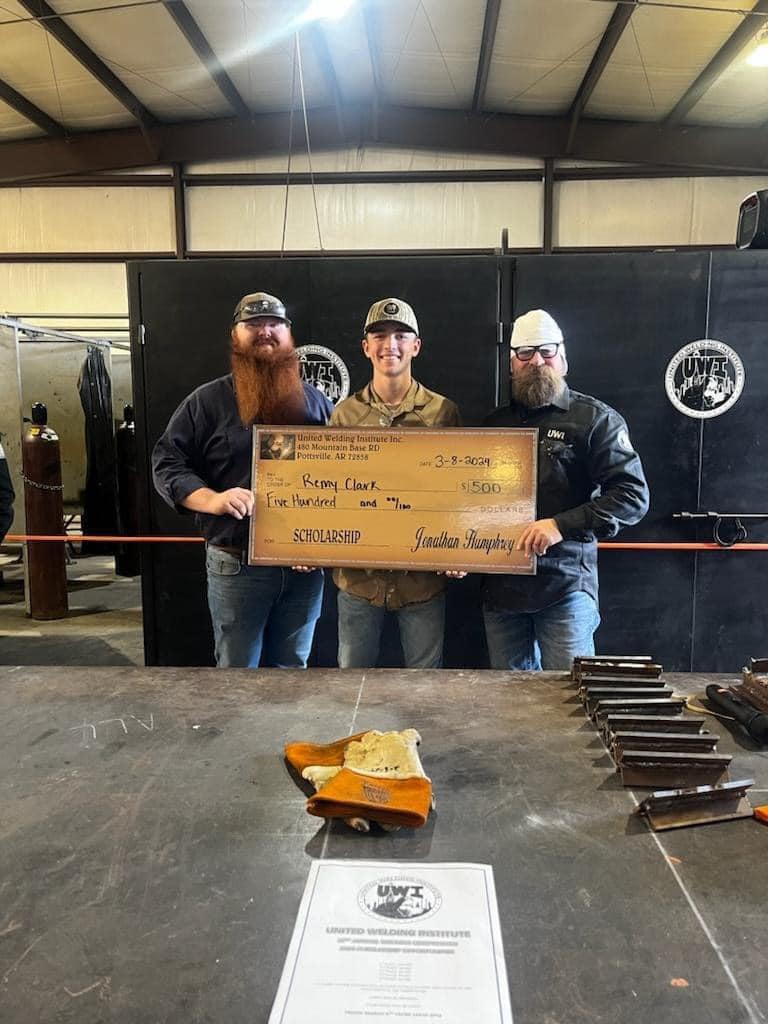 Boy holding large scholarship check next to two men