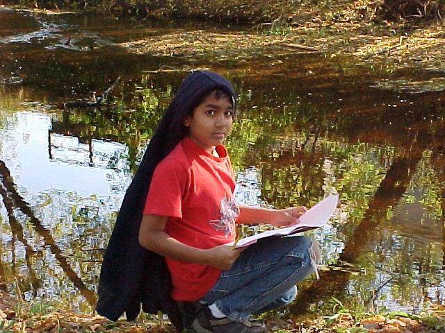 Kid with a notebook sitting beside a river