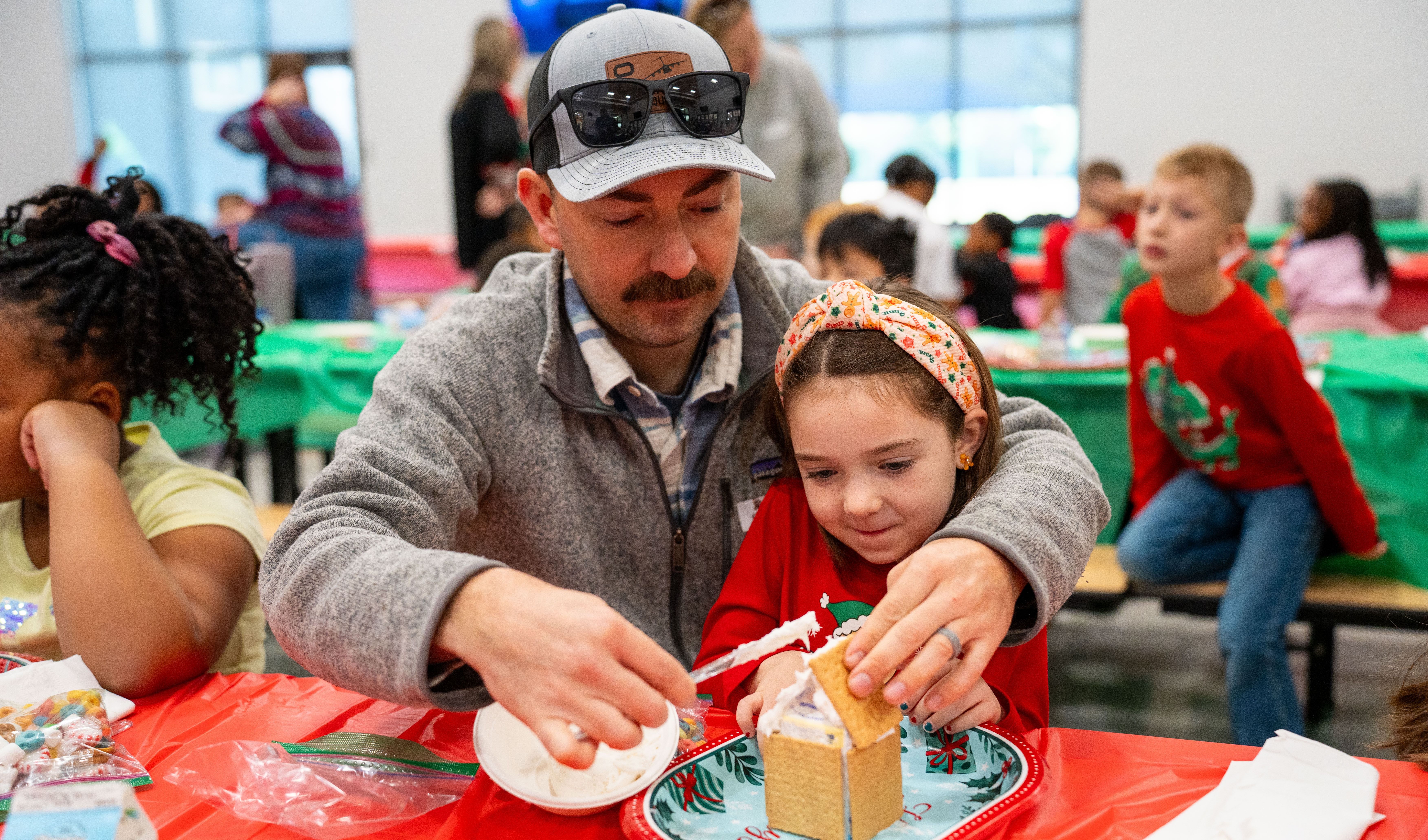 dad helping daughter build gingerbread house