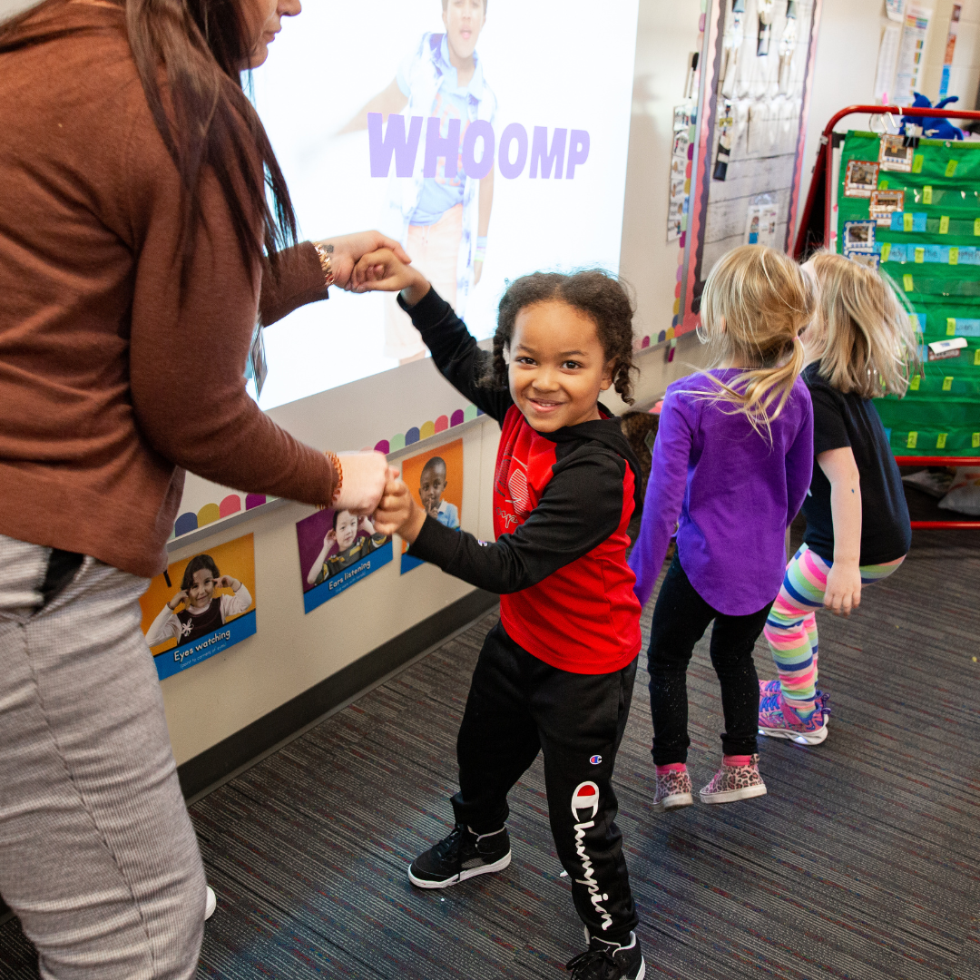 Preschool student dancing with teacher in a sing-a-long extercise