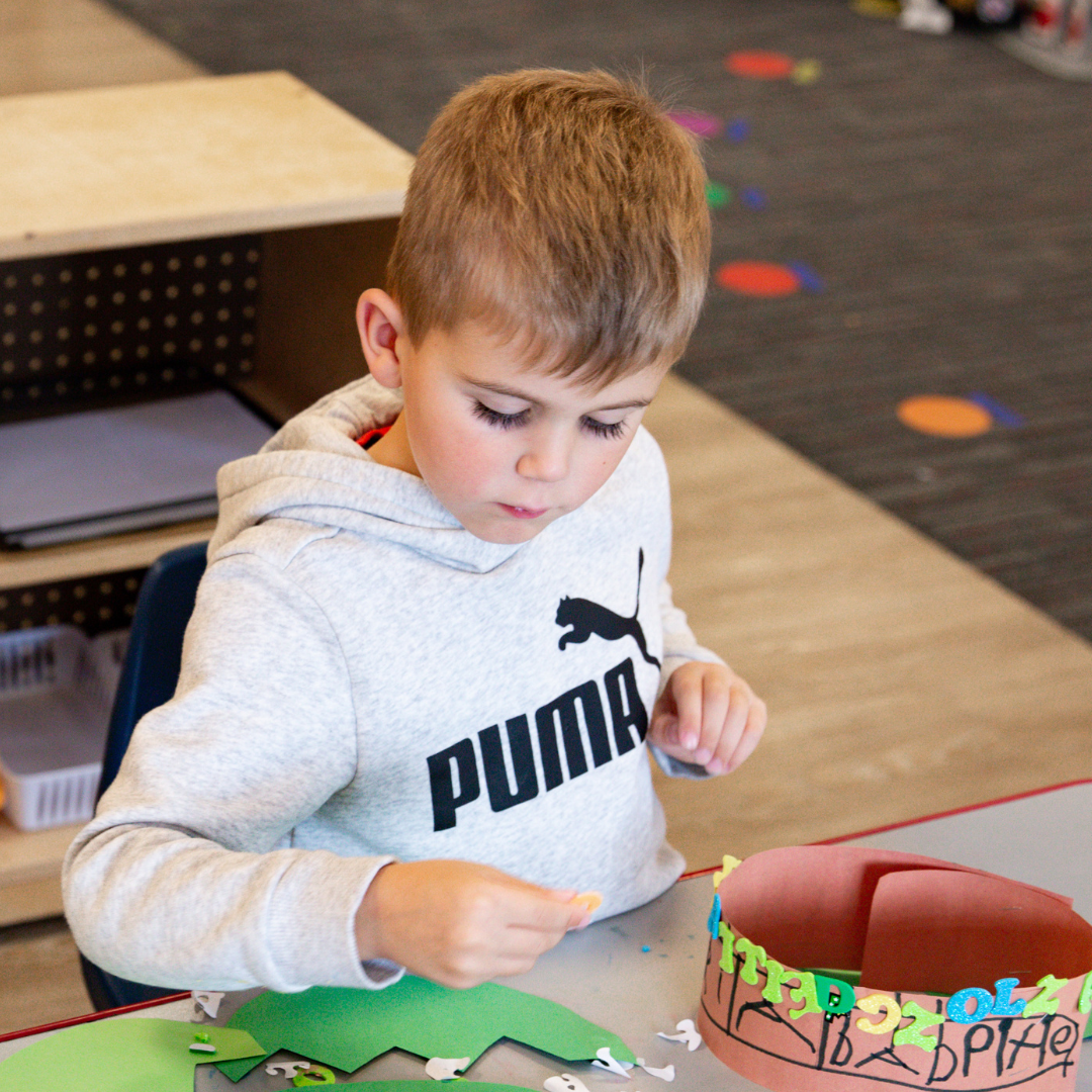 Male preschool student creating a crown during arts and crafts project time