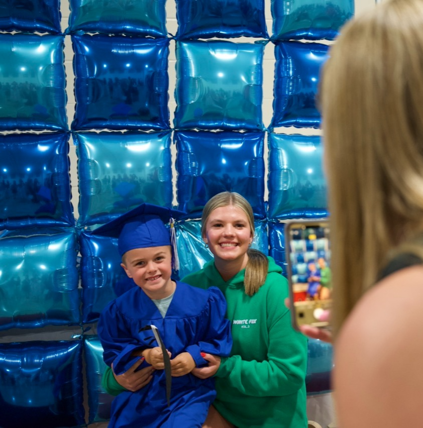 Hoover preschool student at graduation posing for a photo with their sibling