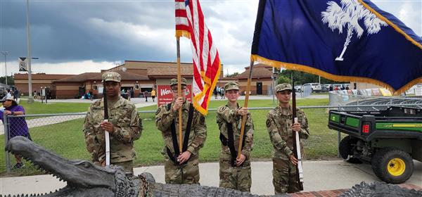 four color guard students holding flags and rifes