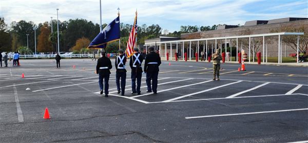 four colorguard students facing away from the camera in a parking lot