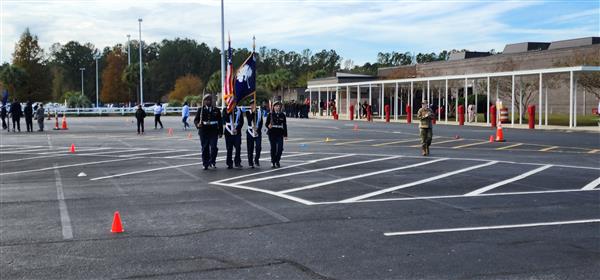 four color guard studnents at a distance holding the flags