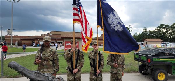 four color guard students holding flags and rifes