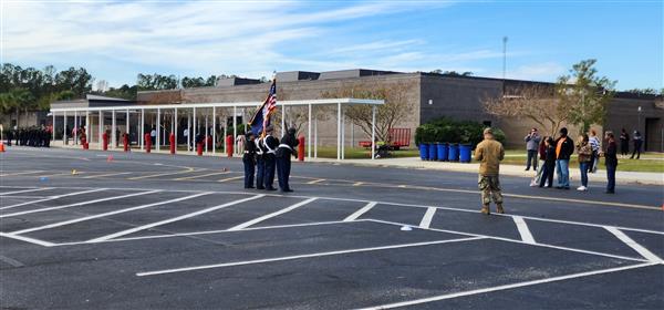 four color guard students in a parking lot facing towards a building