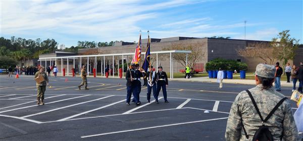 four color guard students with flags in a parking lot