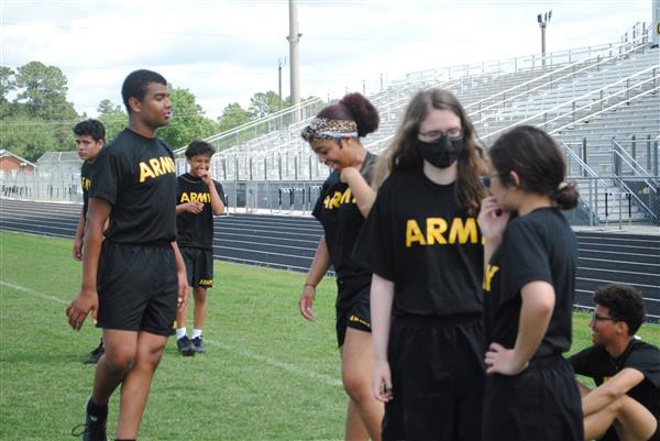 students outdoors on the field with the track behind them