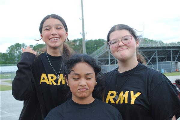 three students outdoors smiling for the camera