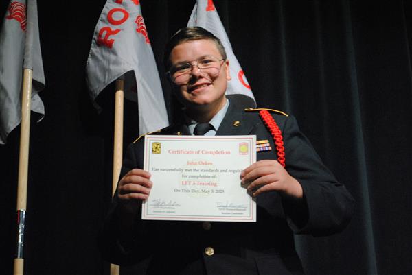 student on stage holding a certificate