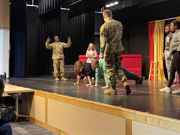 two students doing pushups on stage