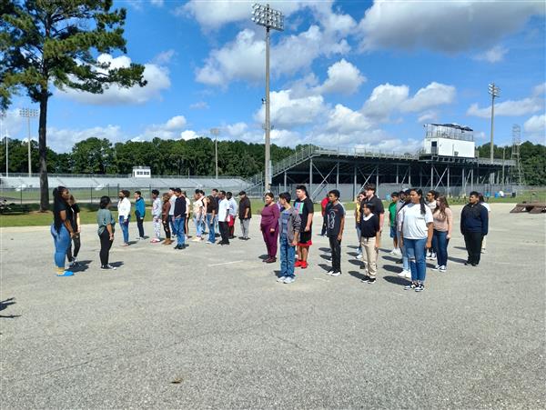 students lined up in rows in a parking lot