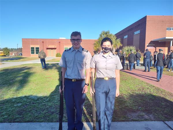 two students smile for the camera outside