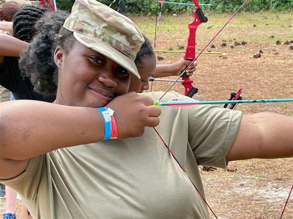 student smiles while drawing a bow