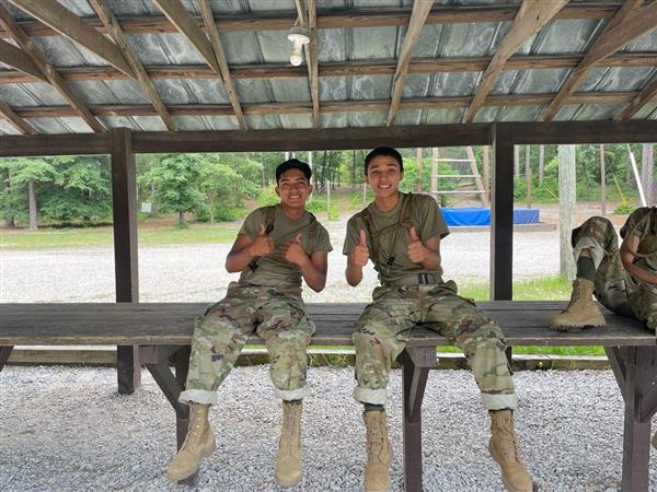 two students sit on a table in an outdoor pavilion