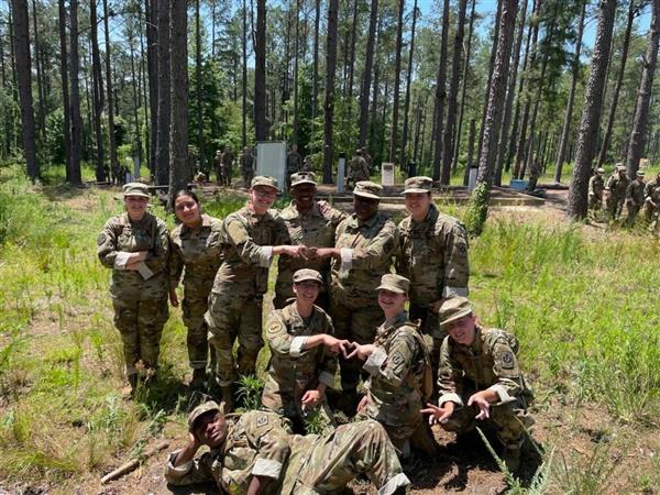 a group of ten students poses in front of trees