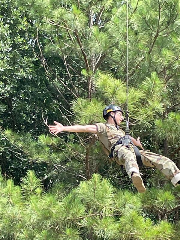 student on a zipline holds his arms out