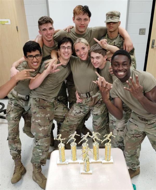 eight students posing with six trophies