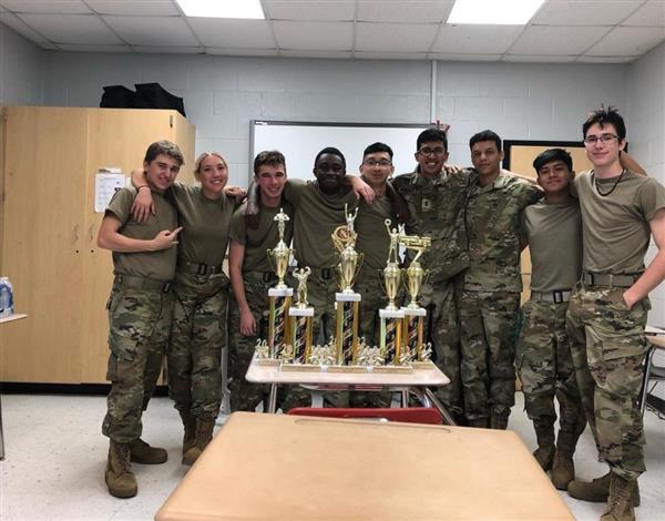 nine students posing with five trophies