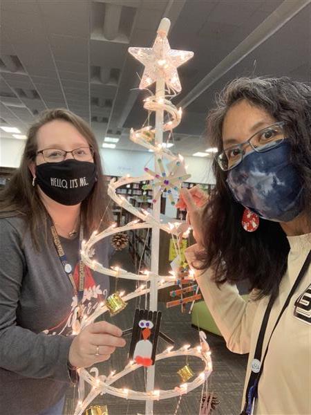 Two people stand with a christmas tree made of a spiraling light rope with a star on top