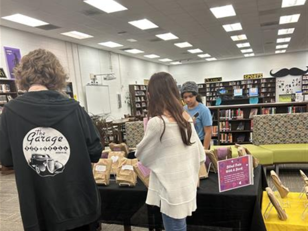 three students look at a display of wrapped books
