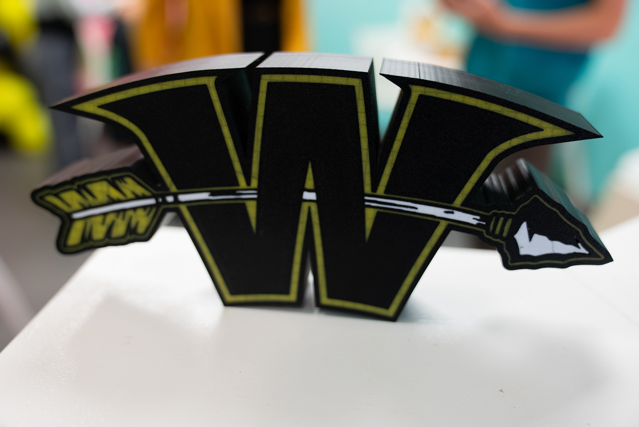A black, white, and green sign with an arrow through the middle of the letter "W."