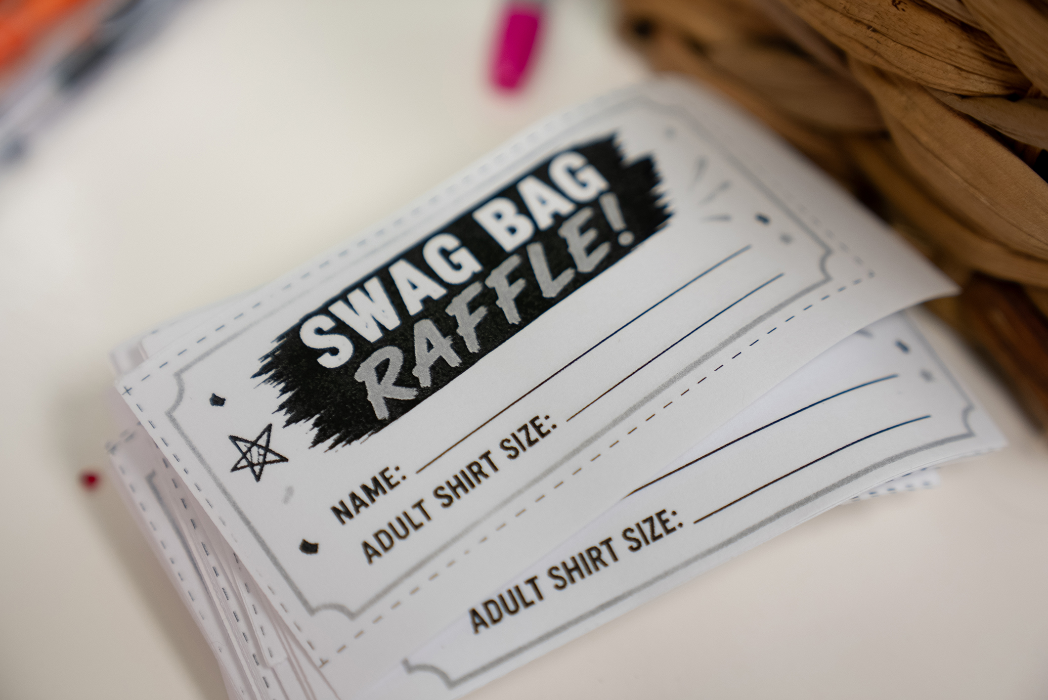 Stacked raffle tickets with "SWAG BAG RAFFLE!" in bold black text. Each ticket has fields for name and adult shirt size.