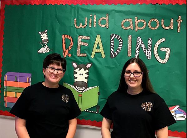 two people standing in front of a wall that says wild about reading