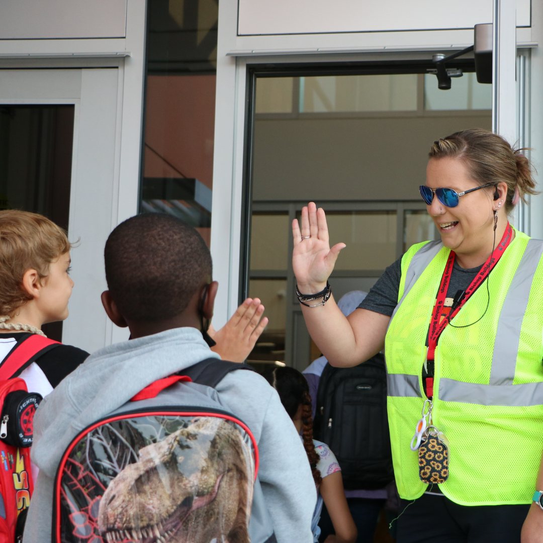 Staff high fiving student walking into school