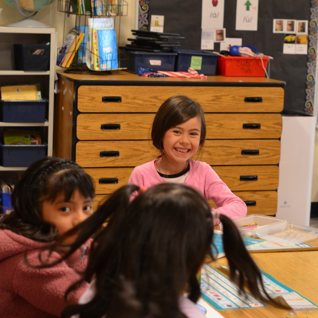 Student smiling at camera from desk