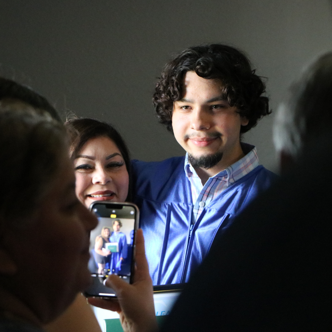 a picture being taken on a cellphone of a LEAP graduate and his mother.