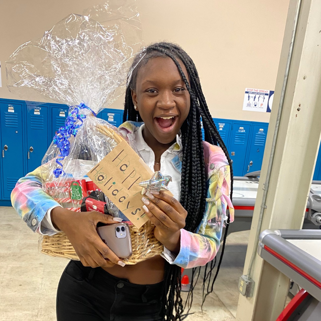 Phoenix student holding a donated holiday gift basket for their fundraising event.