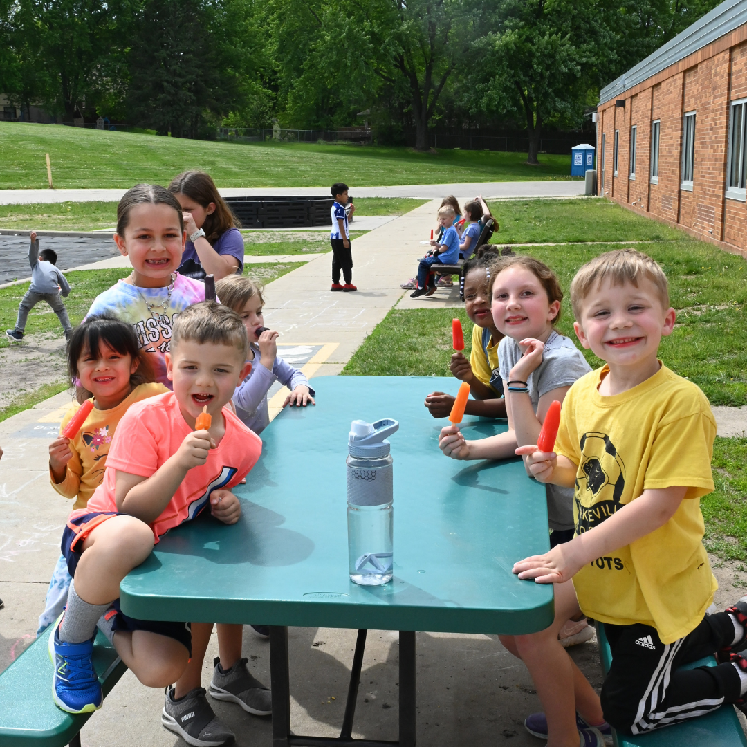 Students outside eating and playing on the picnic table