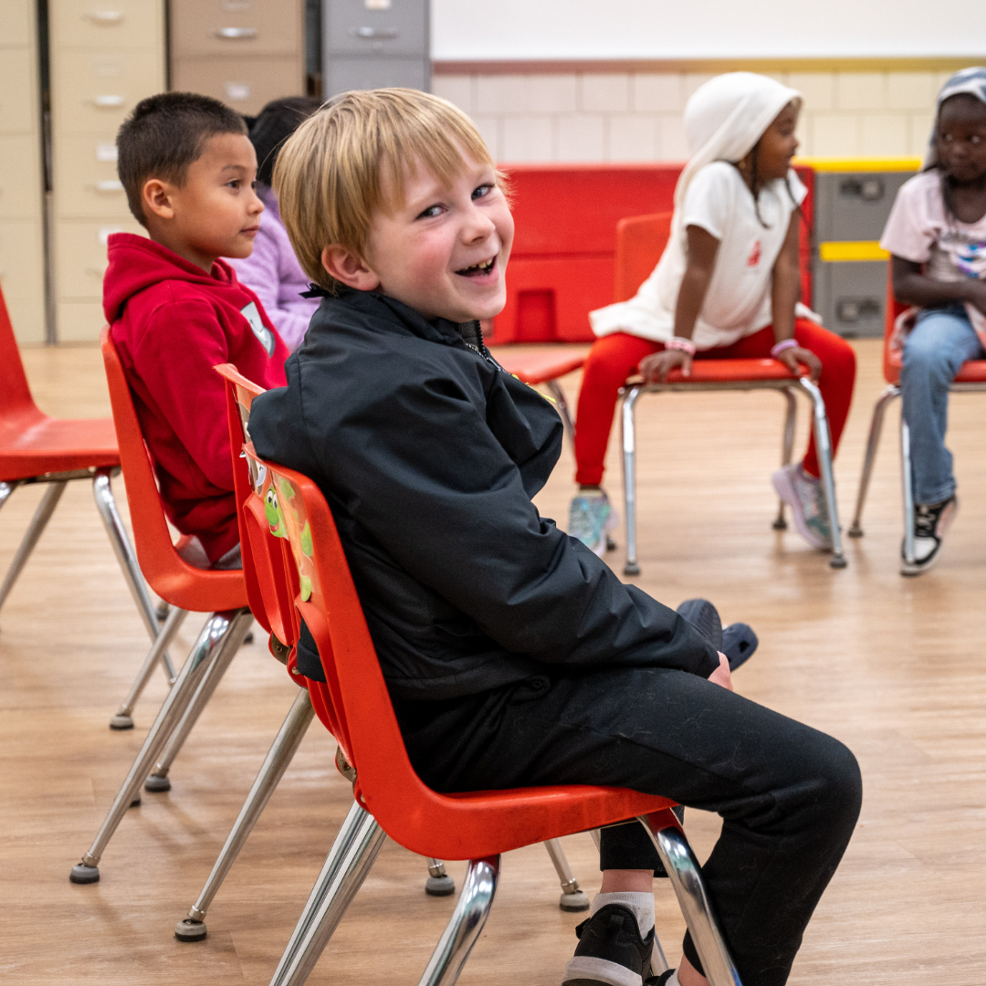 Student sitting in a chair smiling towards the camera.