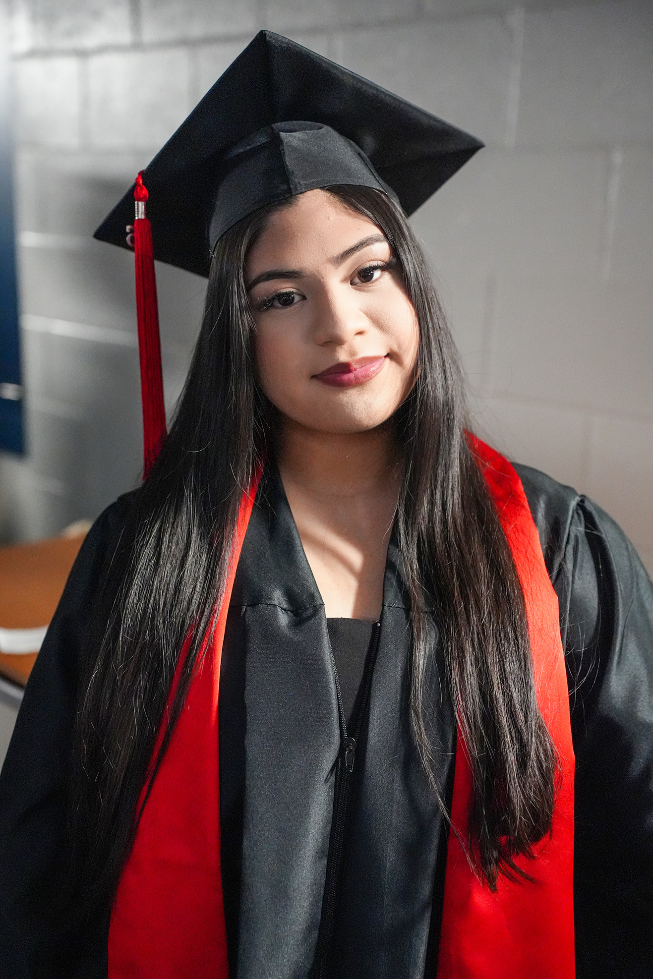 Person in black and red academic regalia, with long hair and a black cap with a red tassel.
