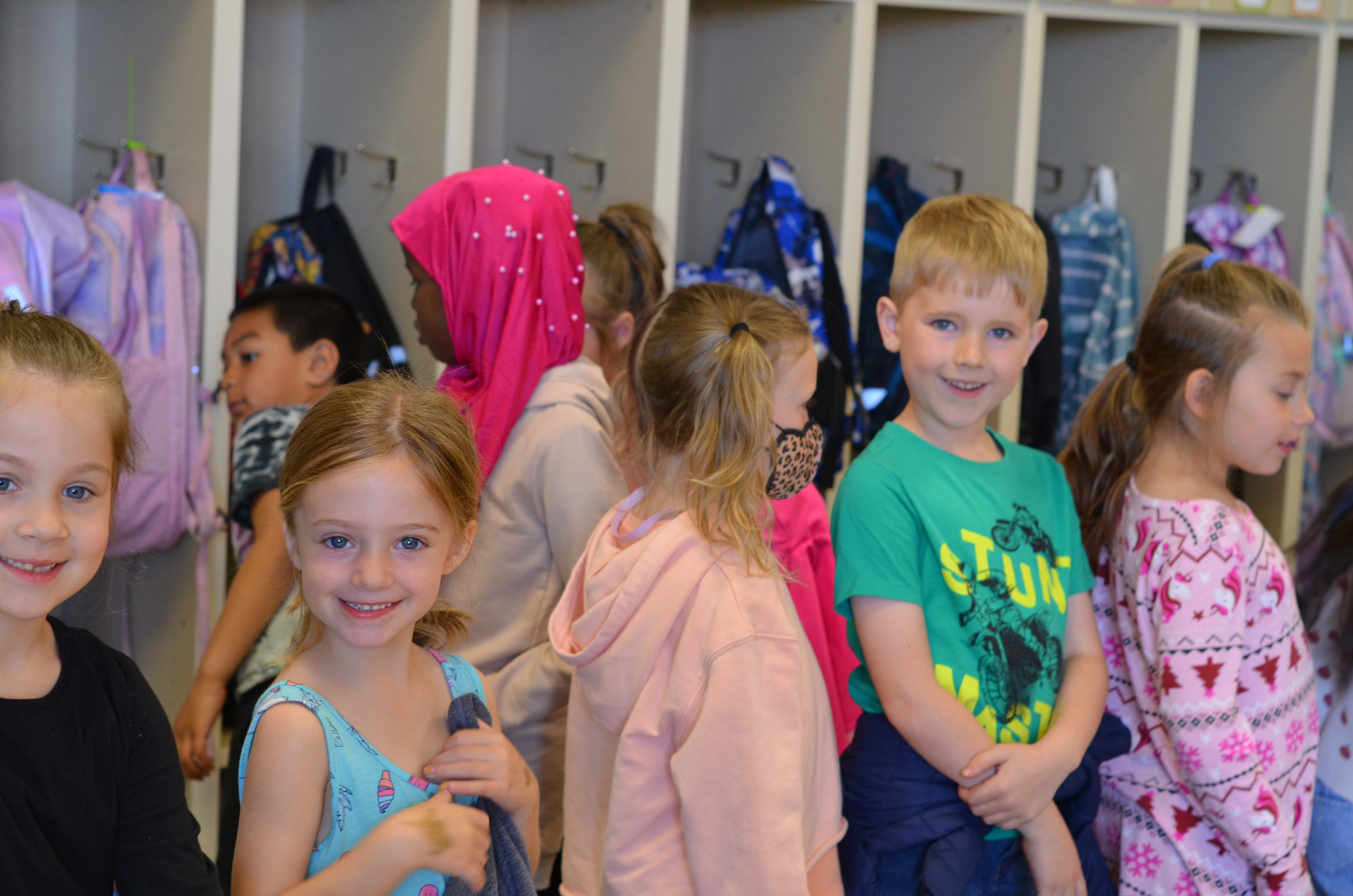 students standing in line to go outside, smiling at camera