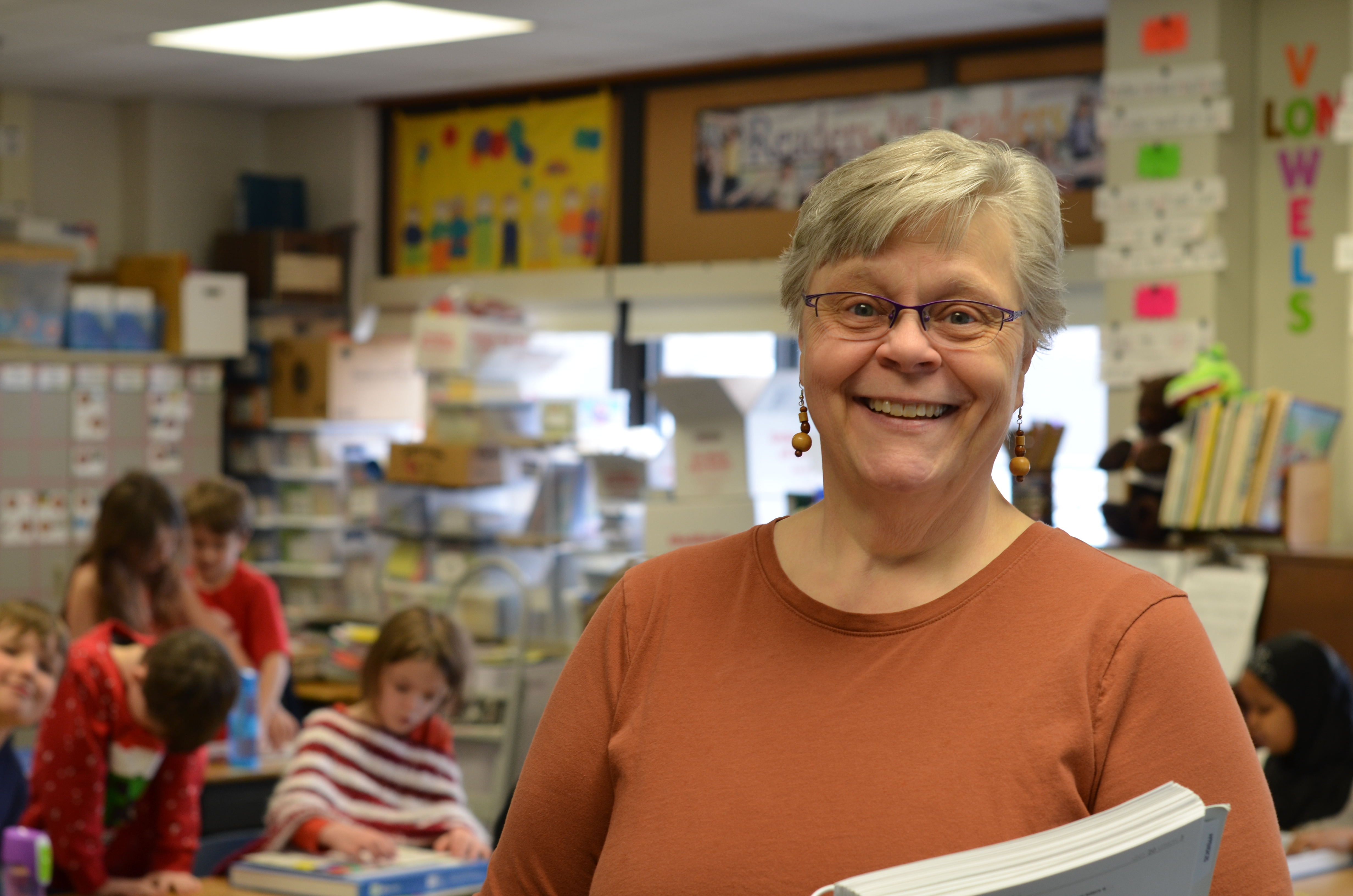 teacher smiling at camera with students behind her