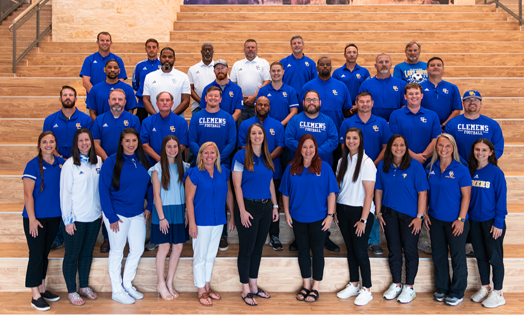 male & female coaches in royal blue & white shirts stand on a staircase