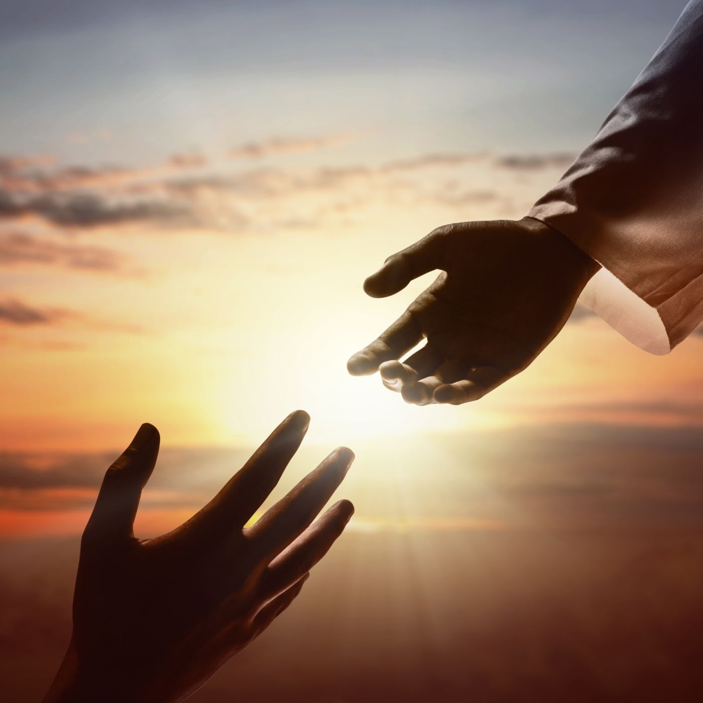 Two hands about to touch with the sun in the background