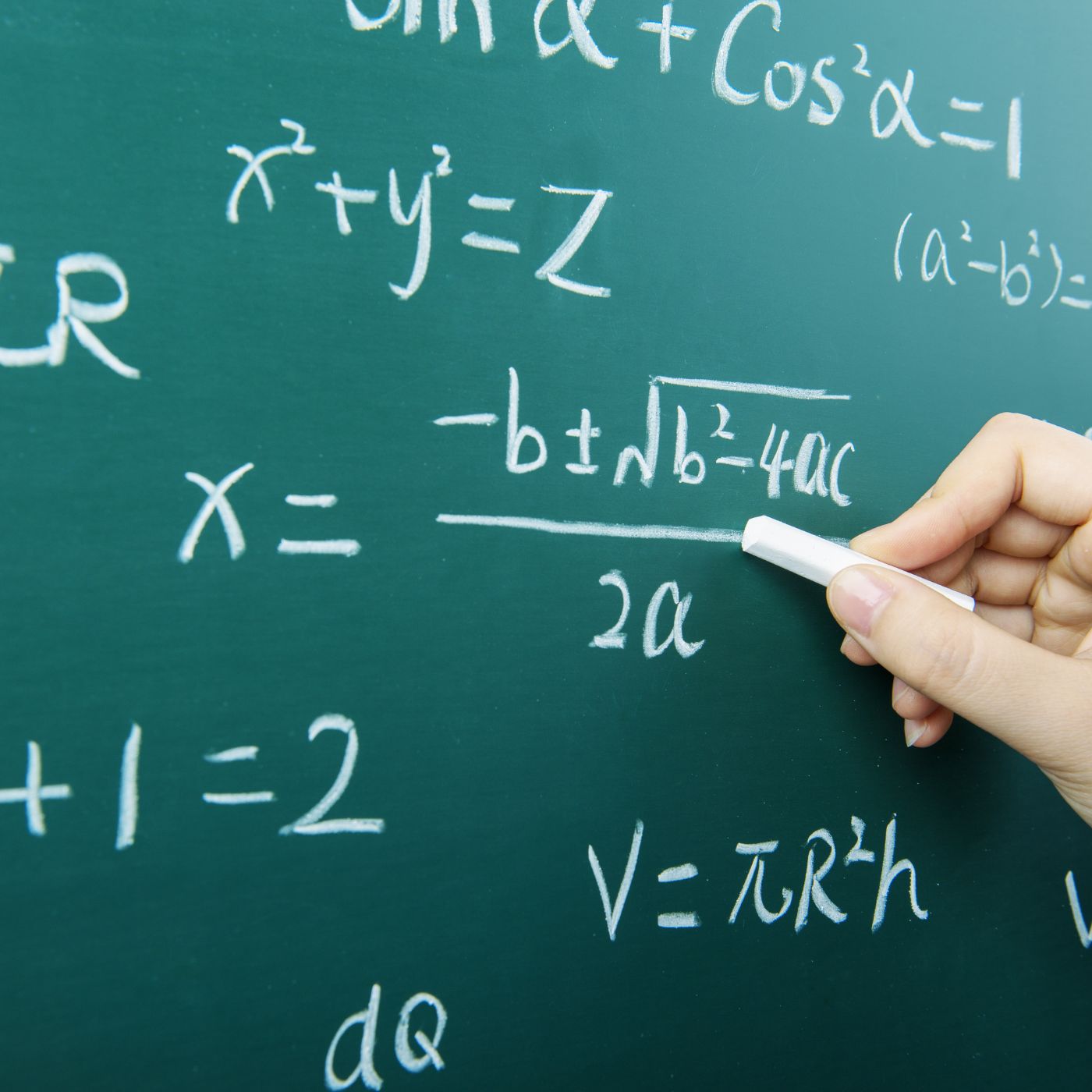 Person writing math equations on a chalkboard