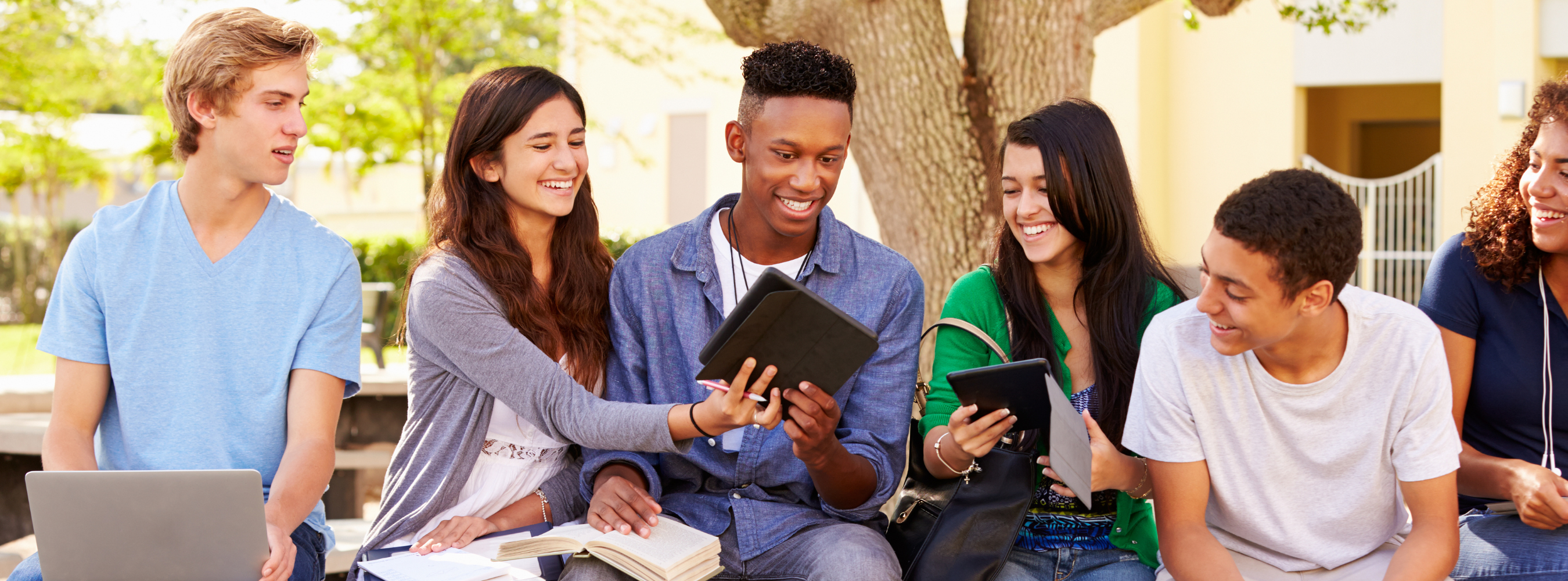 Diverse young adults looking at pictures on tablets