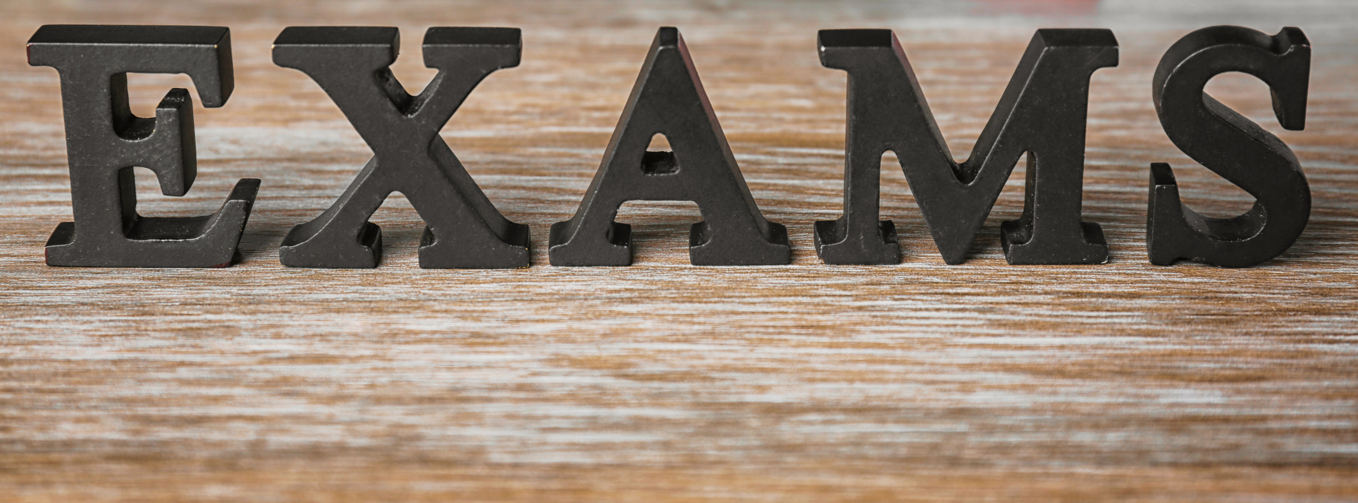 The word EXAMS against a wood background