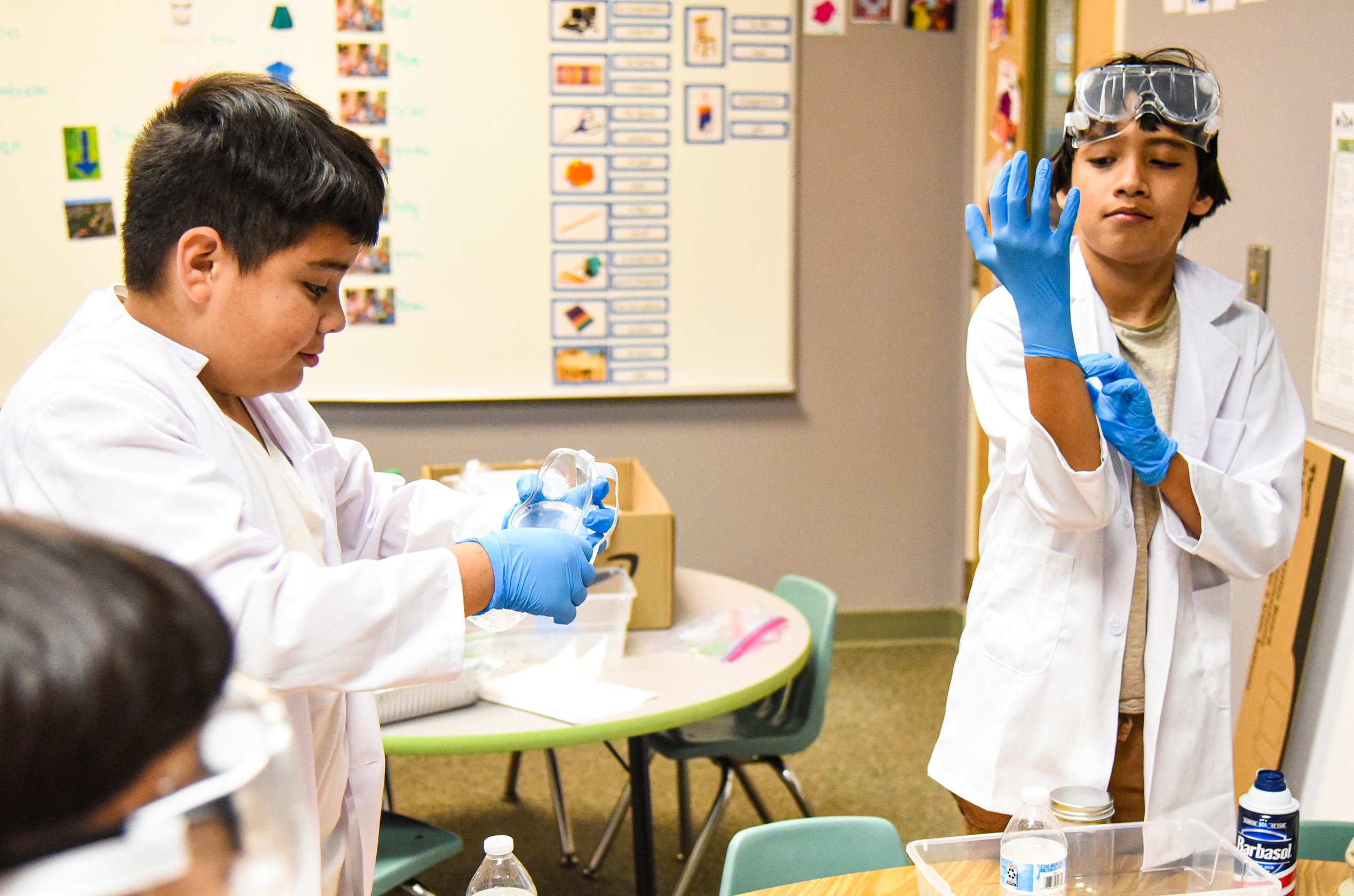 two kids putting on gloves and lab coats