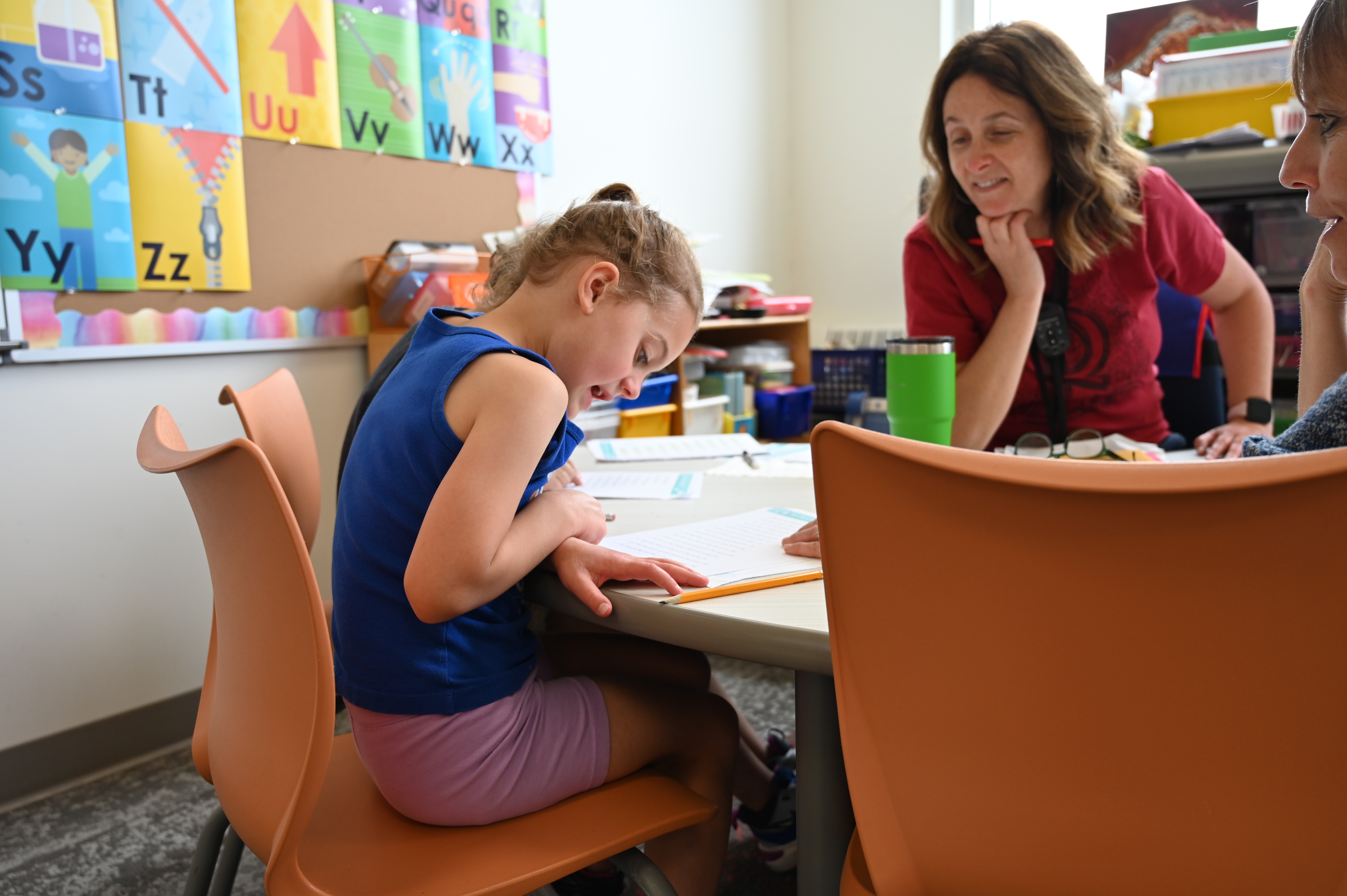 Student working on her reading skills with her teacher observing and helping.