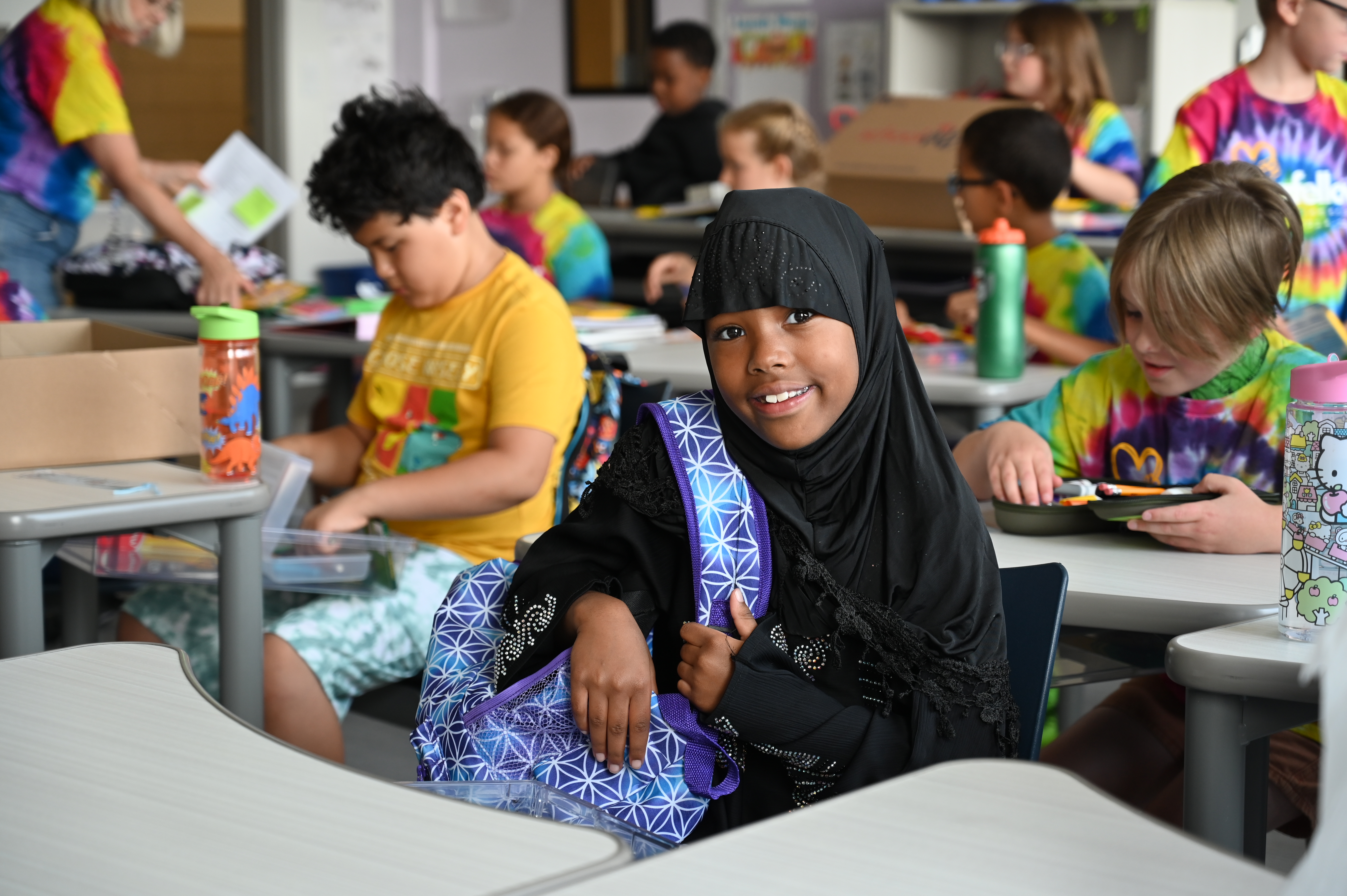 student with backpack smiling at the camera