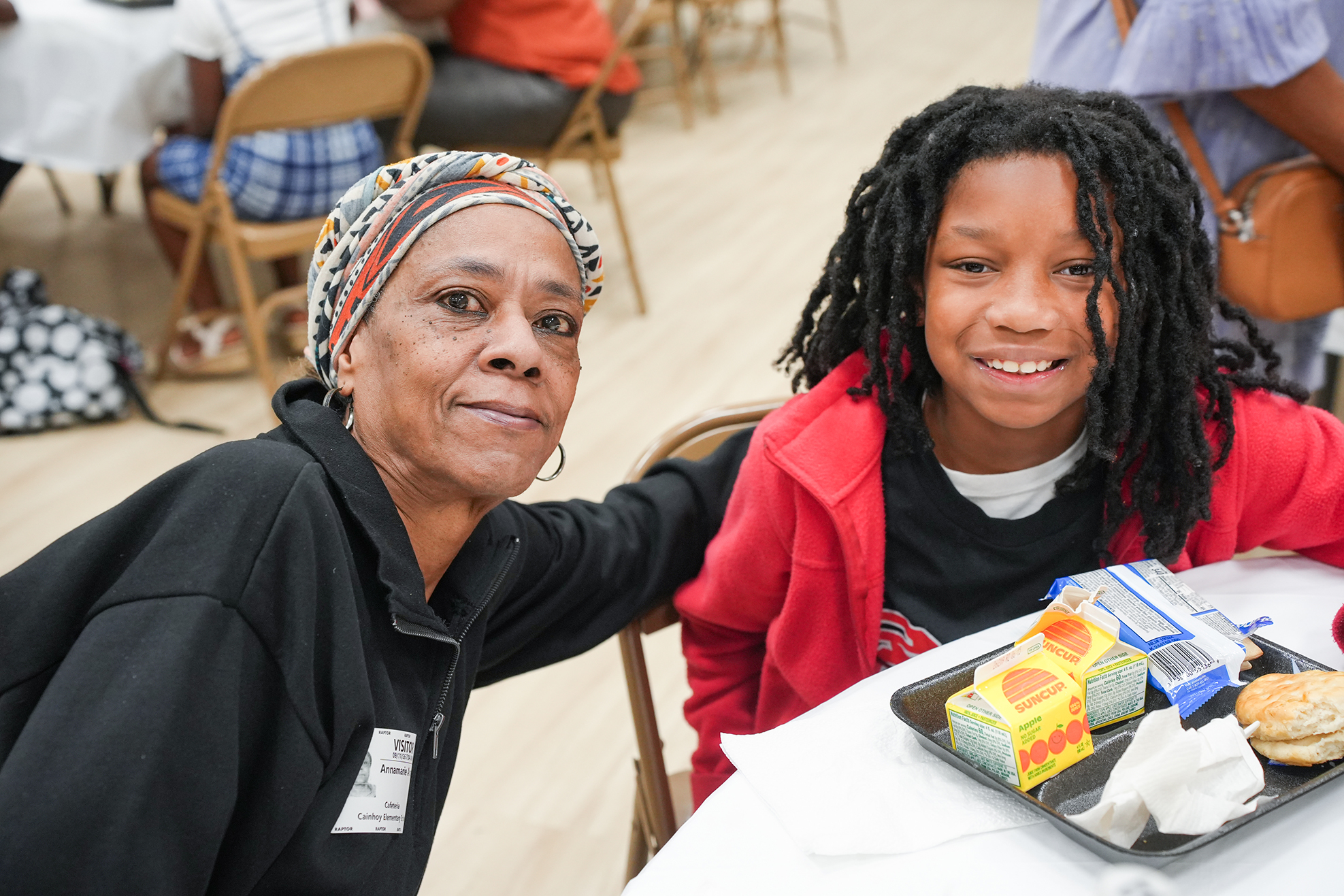 Woman and child seated at a table with a tray of food in front of them.