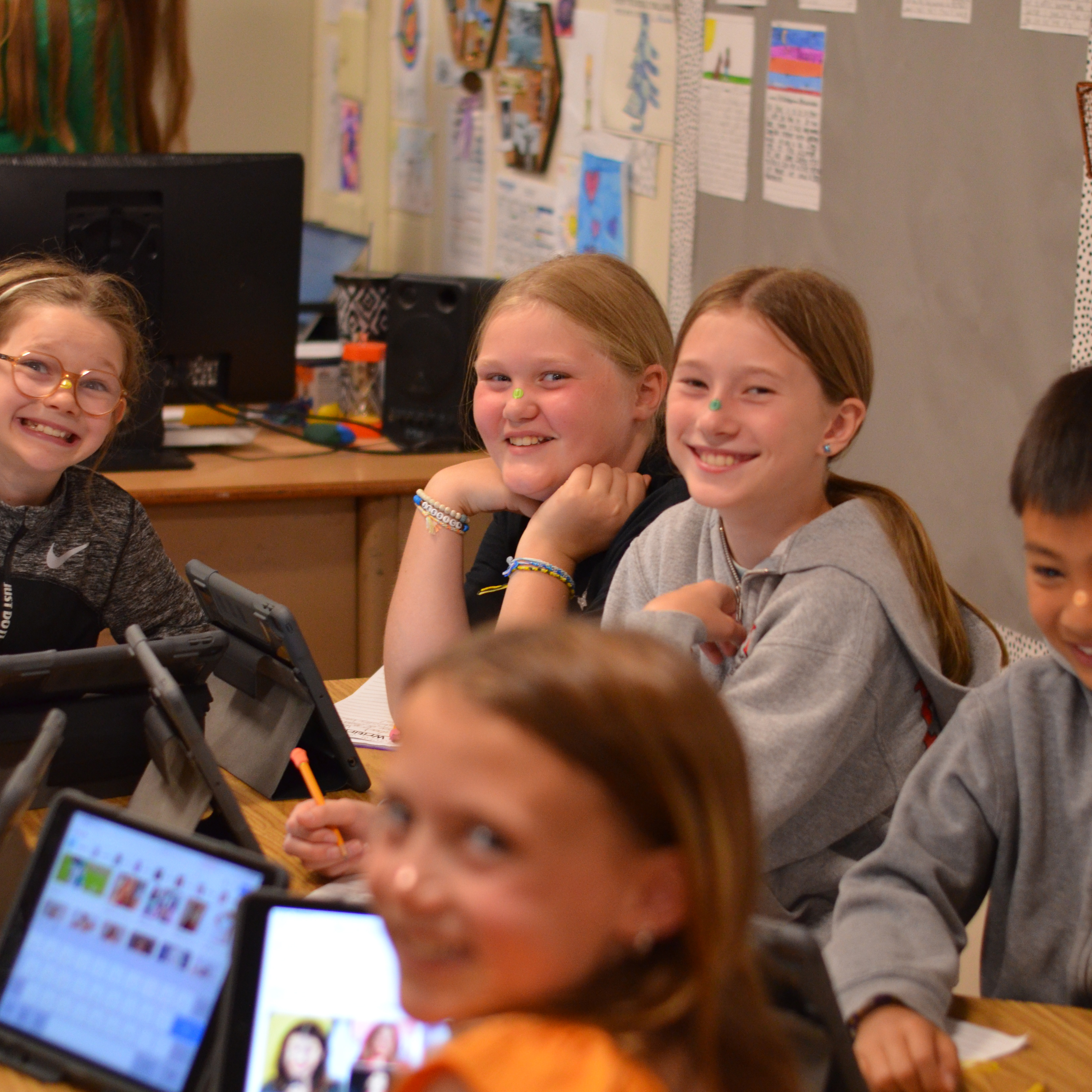 A few students smiling at the camera from across the room